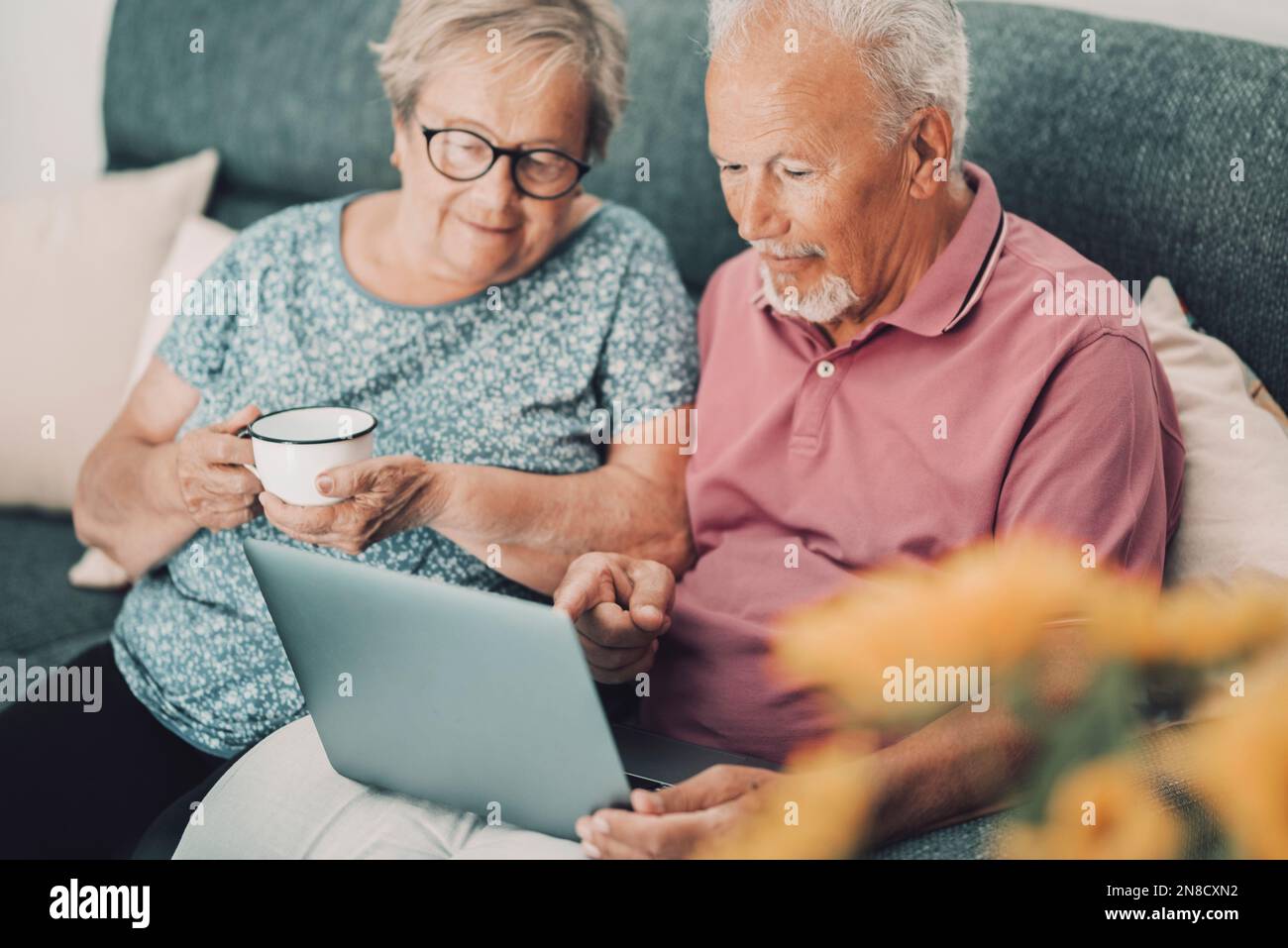 Ruhiges 80s echtes Paar zu Hause, das moderne Laptop-Technologie mit Internetverbindung nutzt, im Internet surft und Zeit und Indoo-Aktivitäten genießt. Stockfoto