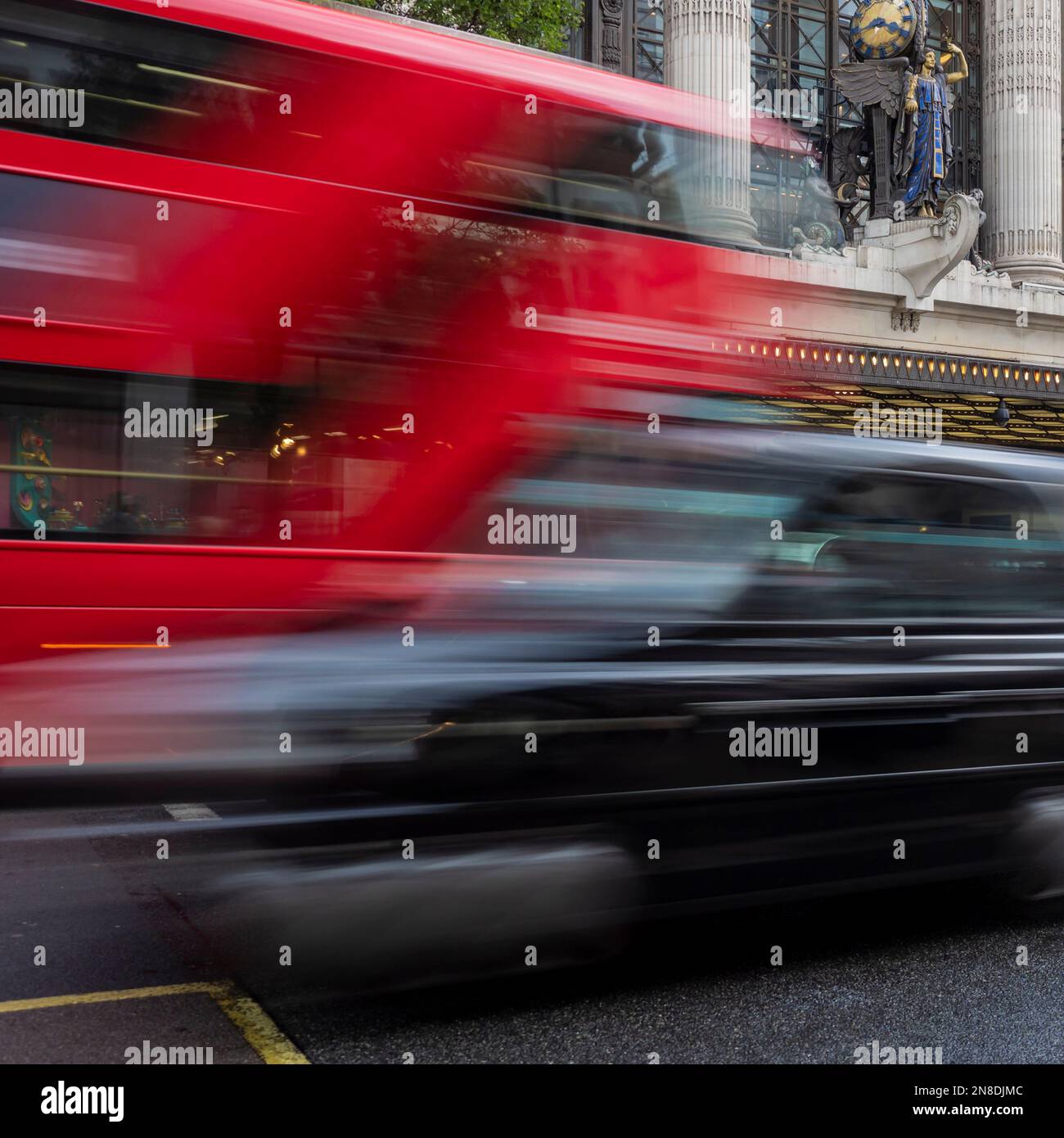 LONDON, Großbritannien - 25. AUGUST 2018: Roter Bus und schwarzes Taxi fahren aneinander vorbei mit Bewegungsunschärfe vor dem Selfridges Store in der Oxford Street Stockfoto