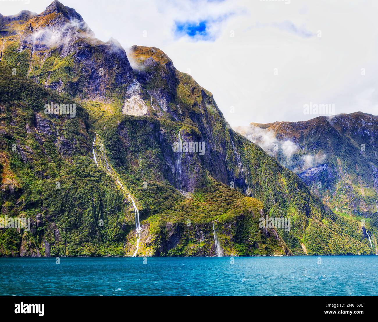 Malerische steile Hänge von Berggipfeln rund um den Milford Sound Fjord in Neuseeland auf einer Bootstour. Stockfoto