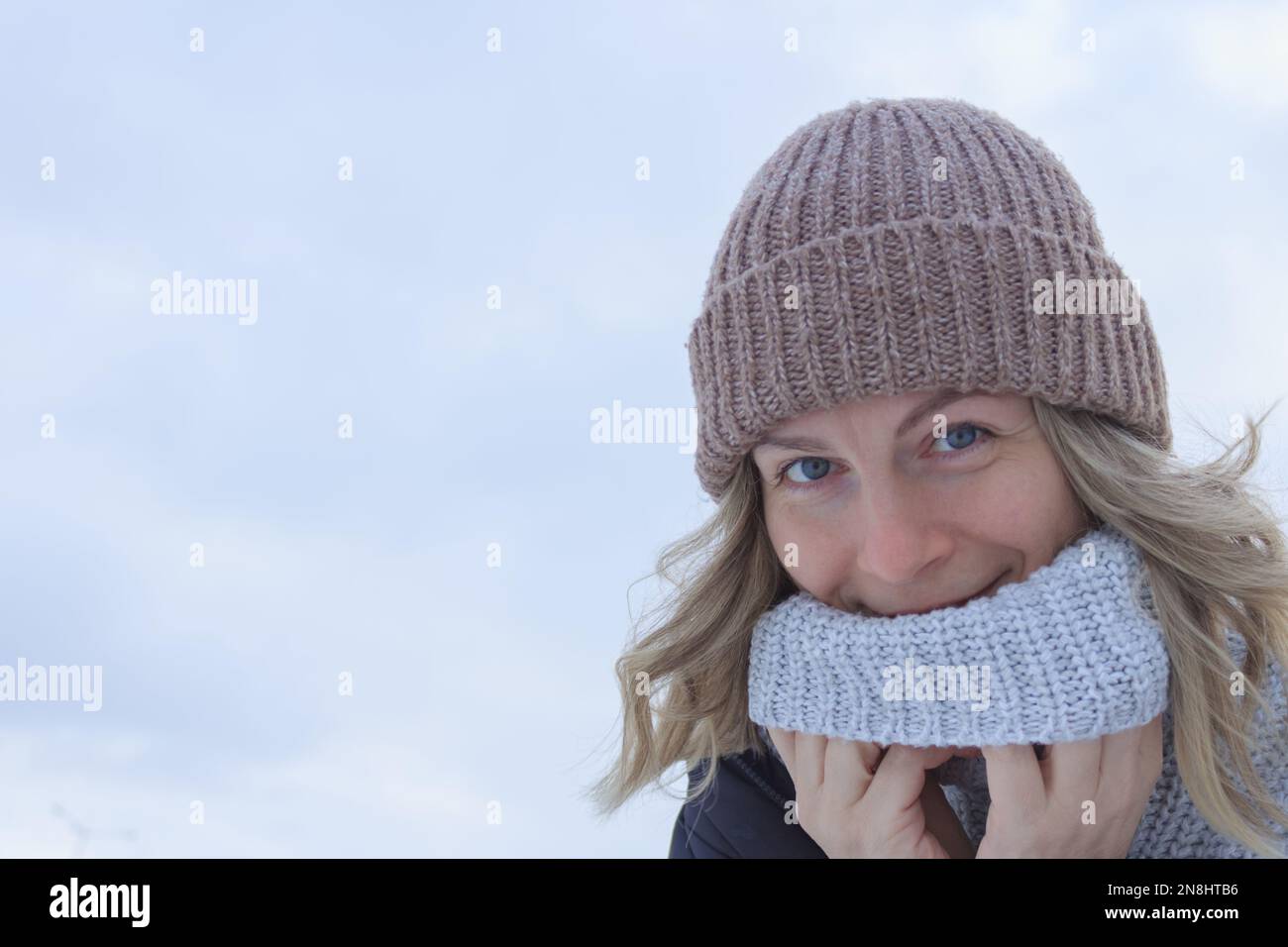 Frau mit blondem Haar in Strickmütze und Pullover auf leichtem Hintergrund Nahaufnahme Stockfoto