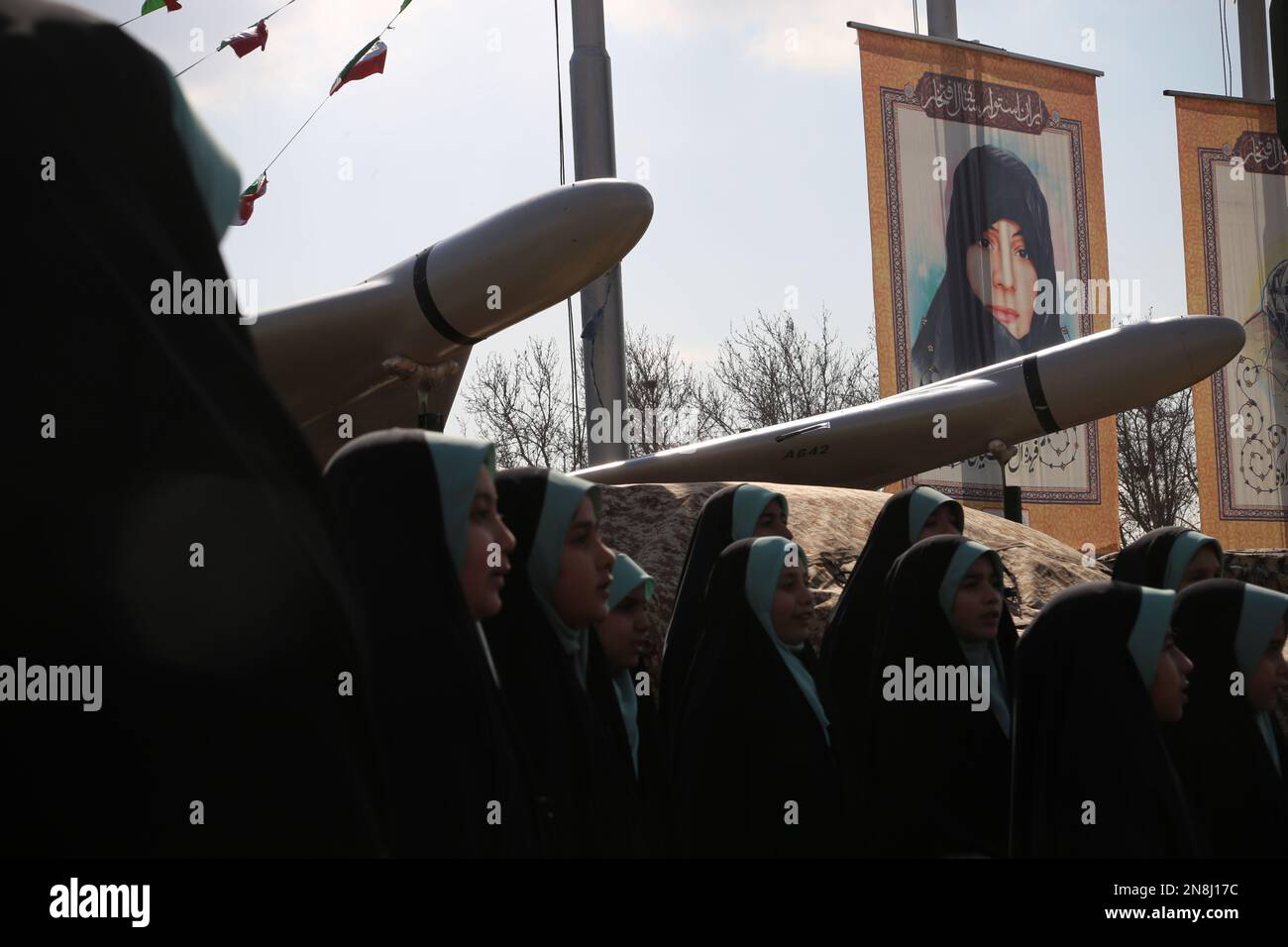 Teheran, Teheran, Iran. 11. Februar 2023. Eine Gruppe verschleierter iranischer Schülerinnen singt den Hymn Hello Commander zur Unterstützung des iranischen Obersten Führers Ayatollah Ali Chamenei unter einem vom Iran hergestellten unbemannten Luftfahrzeug Shahed-136 während der jährlichen Rallye zur Erinnerung an die Islamische Revolution des Iran von 1979 in Teheran, Iran, am 11. Februar 2023. Der Iran feierte am Samstag den 44. Jahrestag der Islamischen Revolution von 1979 inmitten landesweiter regierungsfeindlicher Proteste und verschärfter Spannungen mit dem Westen. Zehntausende Iraner begaben sich heute in Teheran und anderen Städten auf die Straße, um die 44. Jahre zu feiern Stockfoto