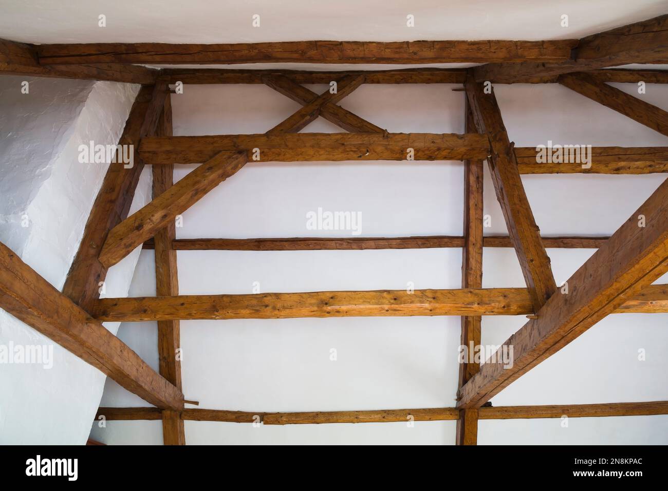Weiße raue Decke und originales Holzgerüst mit Balken mit Mortis- und Sehnenfugen im Dachgeschoss im alten französischen Regimehaus aus den 1809 Jahren. Stockfoto