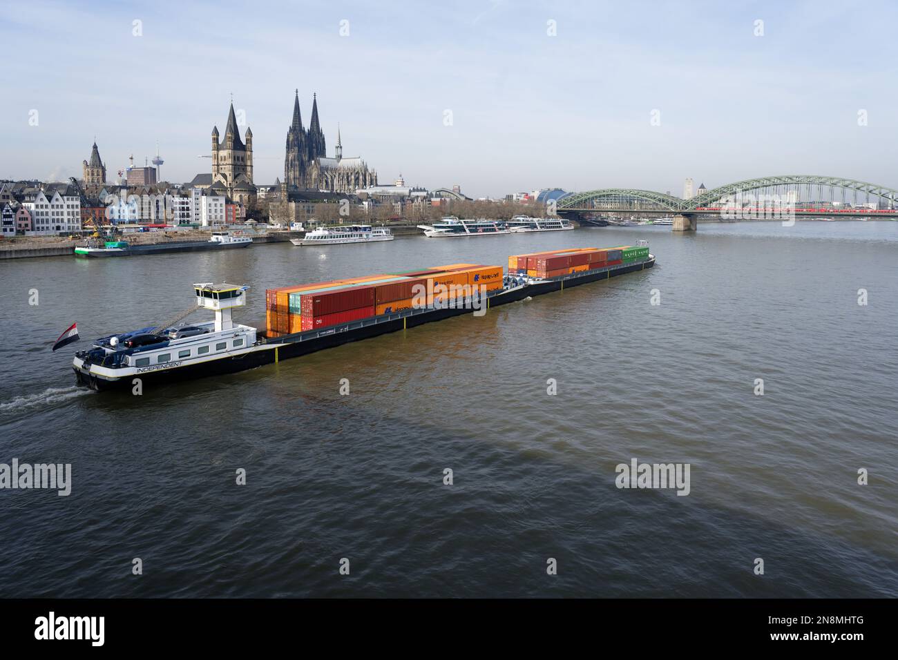 Ein langes Containerschiff mit einem Schubschiff fährt auf dem rhein durch köln Stockfoto