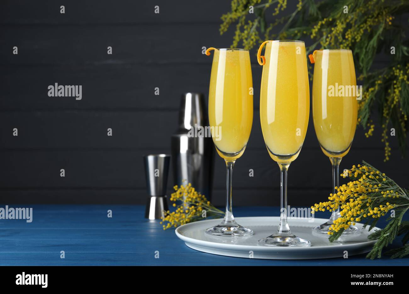 Gläser Mimosa-Cocktail mit blühenden Zweigen auf hellblauem Holztisch. Platz für Text Stockfoto