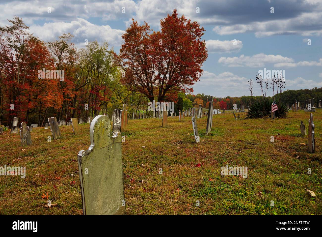 Ein Friedhof umgeben von bunten Herbstbäumen Stockfoto