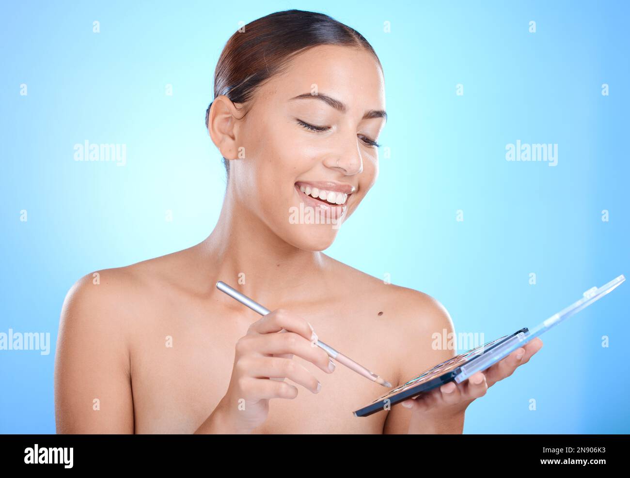 Make-up, Beauty Palette und Frau isoliert auf blauem Hintergrund für Gesicht, Hautpflege und Produktwerbung. Model, Künstler oder junge Person mit Kosmetik Stockfoto