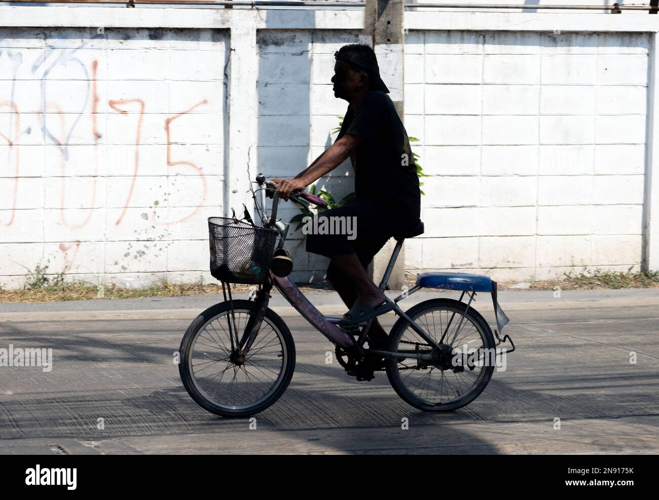 Schwarze Silhouette eines Fahrradfahrers in einer Stadtstraße. Stockfoto