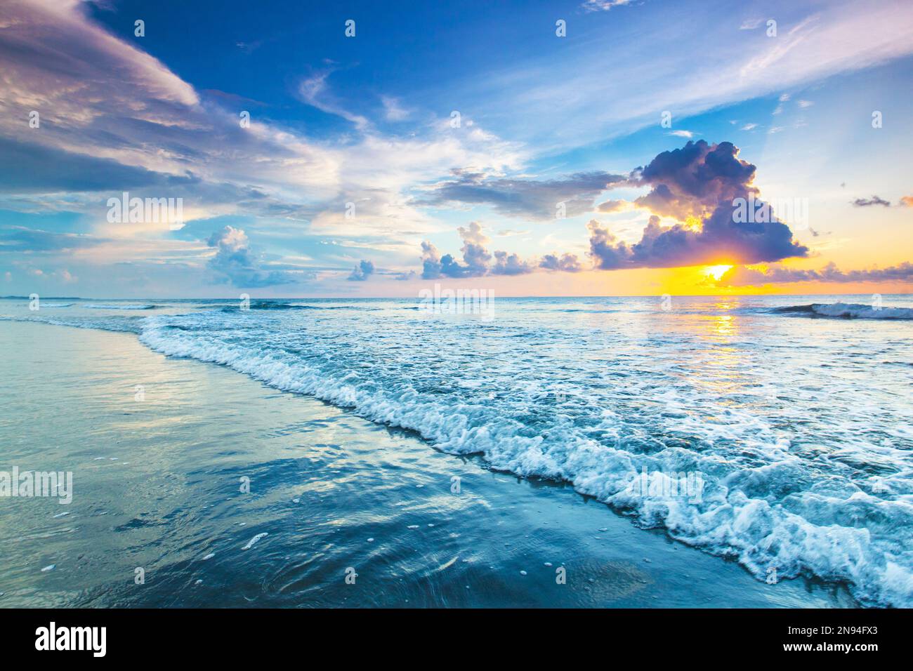 Sonnenaufgang oder Sonnenuntergang am Strand über dem tropischen Meer und Himmel mit Wolken Stockfoto