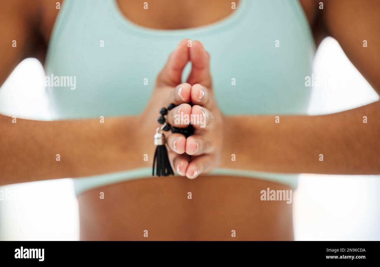 Mala-Perlen helfen bei der meditativen Fokussierung. Eine unbekannte Frau, die mala-Perlen hält und in einem Yoga-Studio meditiert. Stockfoto