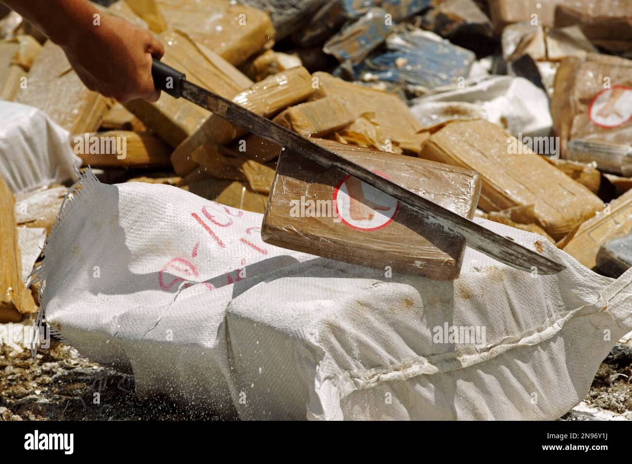 A police officer cuts packages of seized cocaine with a machete before ...