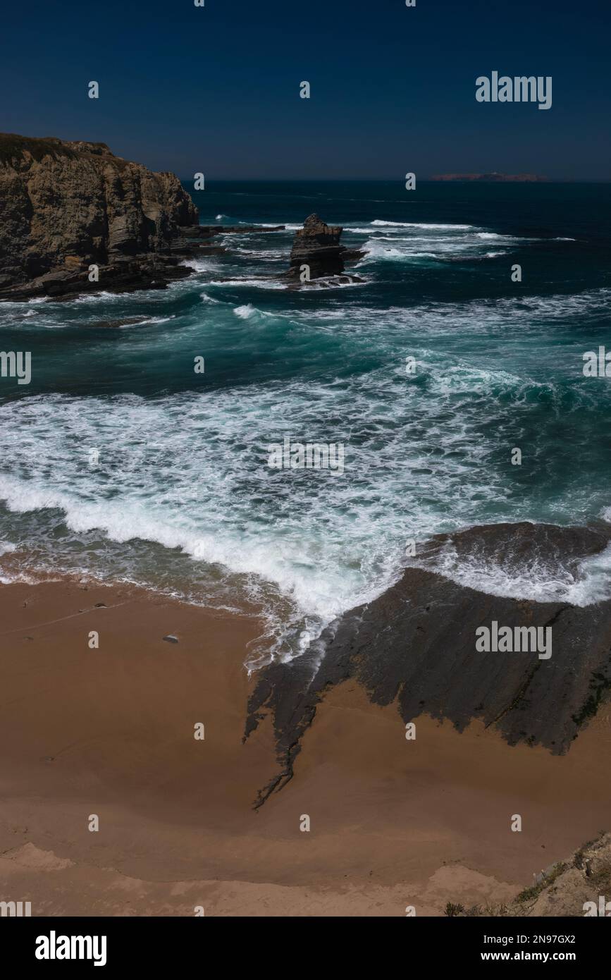 Die steilen Klippen von Berlenga Grande, der größten der Berlenga-Inseln, sind von dieser verlassenen Sandbucht an der zerklüfteten Küste von Cabo Carvoeiro in Peniche im Stadtteil Leiria im Zentrum Portugals deutlich zu sehen. Die Insel, eine Oase für Meereslebewesen und Seevögel, liegt etwa 10km km (6,2 Meilen) im Atlantischen Ozean. Stockfoto