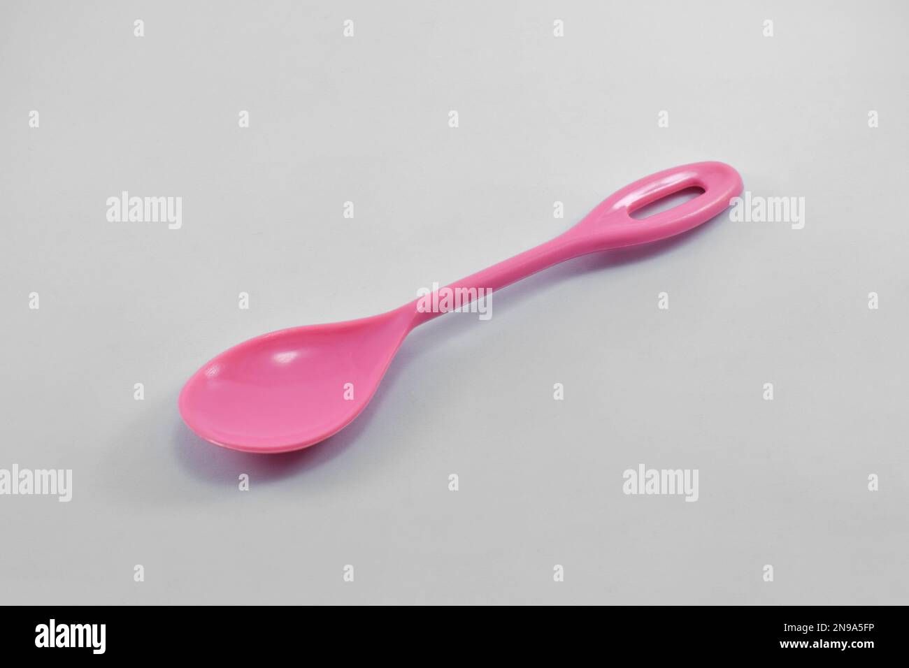 Kleiner rosafarbener Kunststofflöffel isoliert auf weißem Hintergrund. Stockfoto