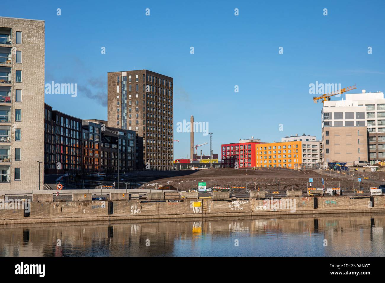 Leerstehendes Grundstück im ehemaligen Hafenbecken Melkinlaituri, umgeben von neu gebauten Wohngebäuden im Bezirk Länsisatama in Helsinki, Finnland Stockfoto
