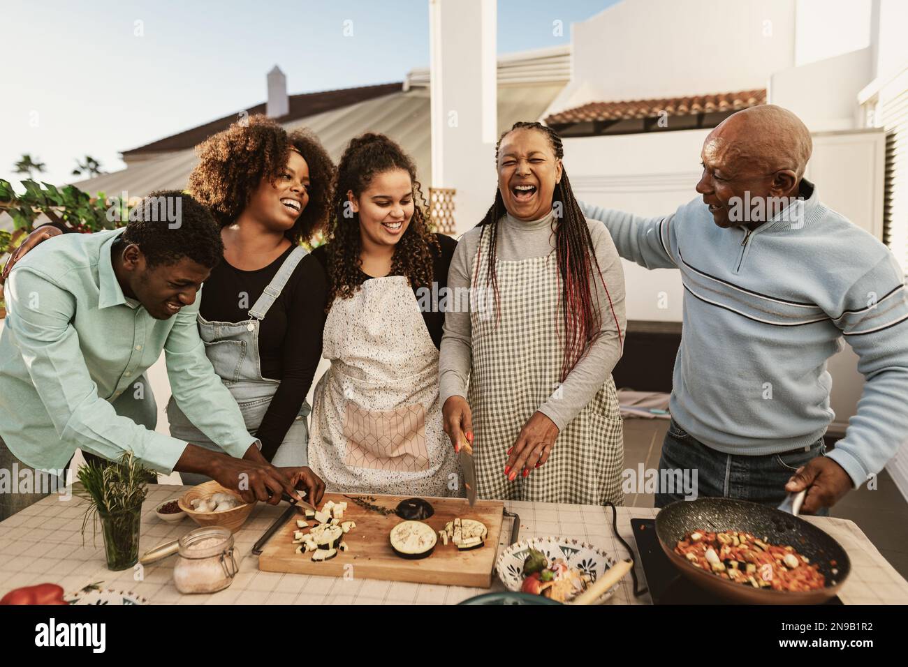 Eine glückliche afrikanische Familie bereitet gemeinsam auf der Terrasse des Hauses ein Speisenrezept zu Stockfoto