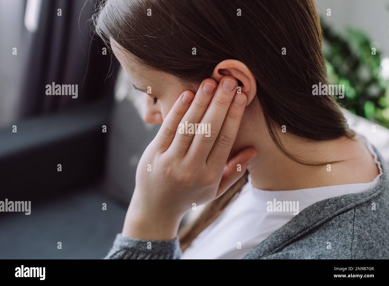 Tinnitus-Konzept. Nahaufnahmen von kranken jungen weißen weiblichen Touch-Plug-Ohrstöpsel leiden an lauten störenden Geräuschen, wenn sie zu Hause auf dem Sofa sitzen. Verärgert Millen Stockfoto