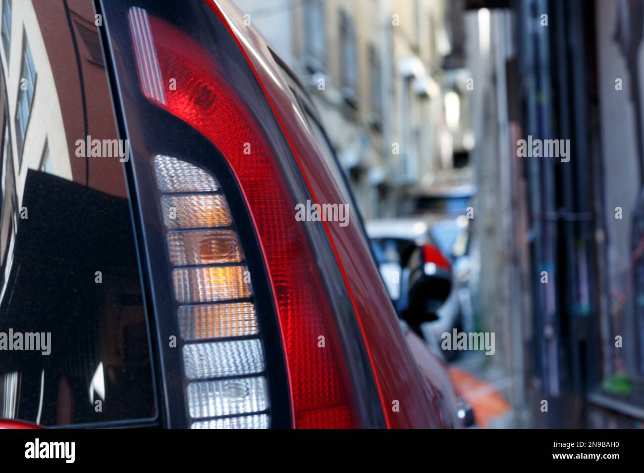 Rotes Auto-Rücklicht mit Reflektion von Gebäuden auf der Straße Stockfoto