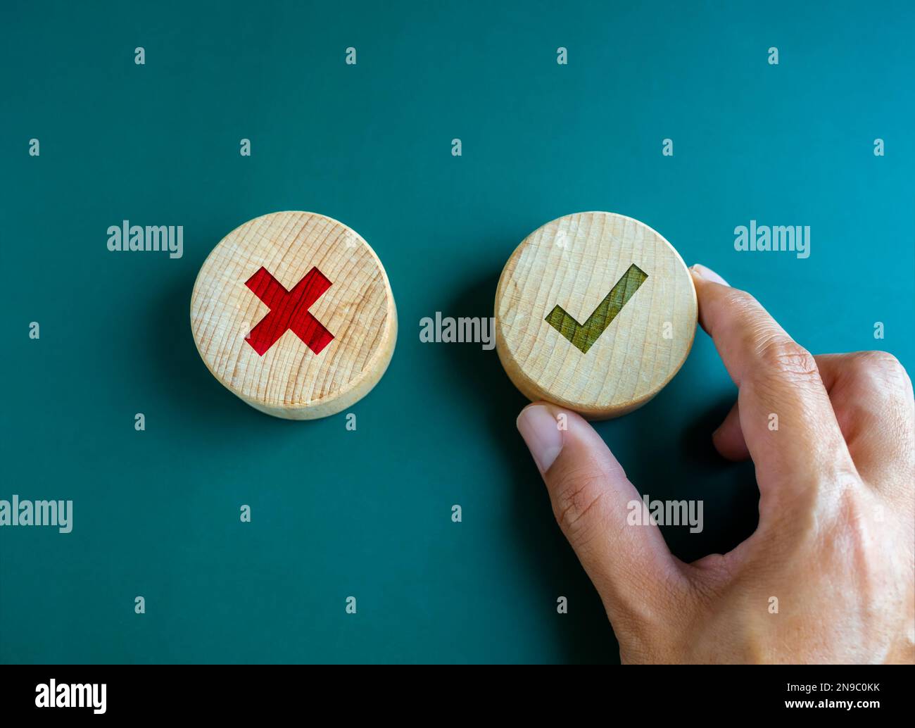 Richtig und falsch. Nahaufnahme grünes Häkchen und rotes X-Symbol auf rundem Holzknopf, grünes Häkchen von der Hand des Unternehmens ausgewählt. Auswahl der richtigen Signatur Stockfoto