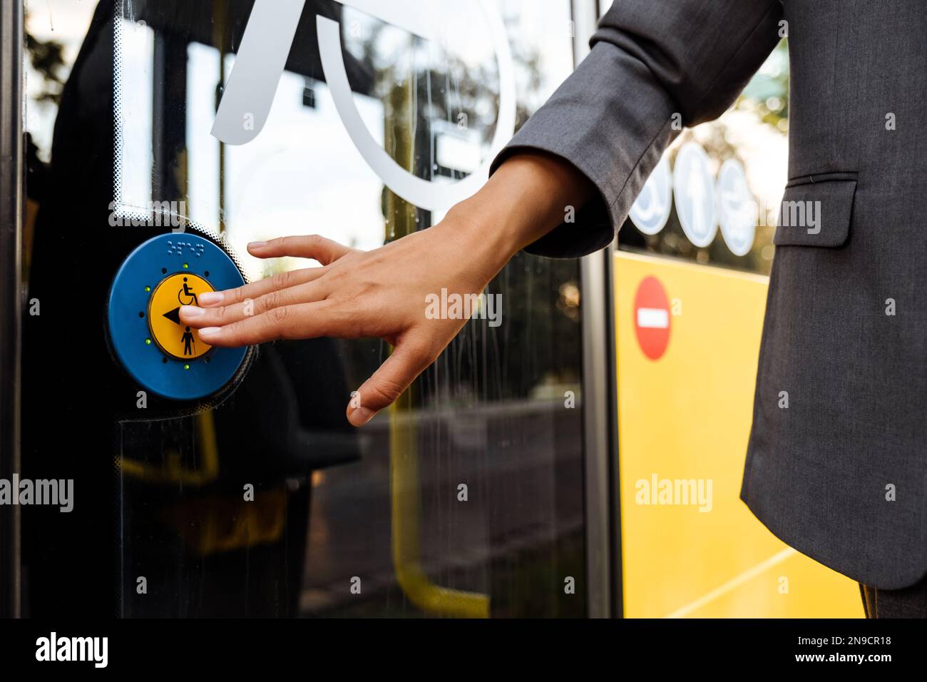 Handbetätigung des blauen Knopfes der behindertengerechten Tür im öffentlichen Bus im Freien Stockfoto