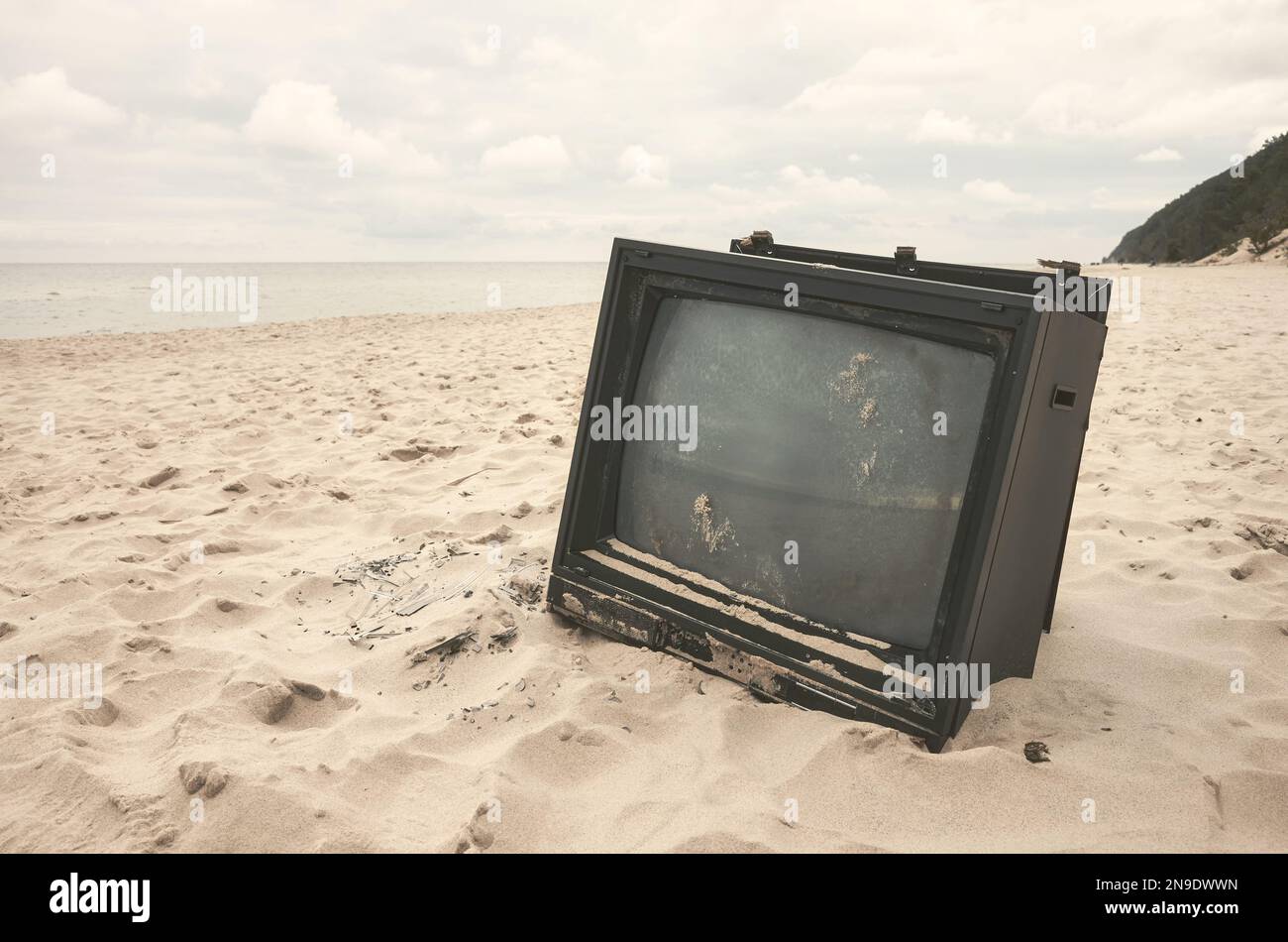 Alte kaputte Fernseher am Strand, Farbtöne aufgetragen. Stockfoto