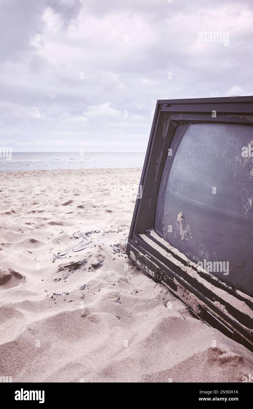 Alte kaputte Fernseher am Strand, Farbtöne aufgetragen. Stockfoto