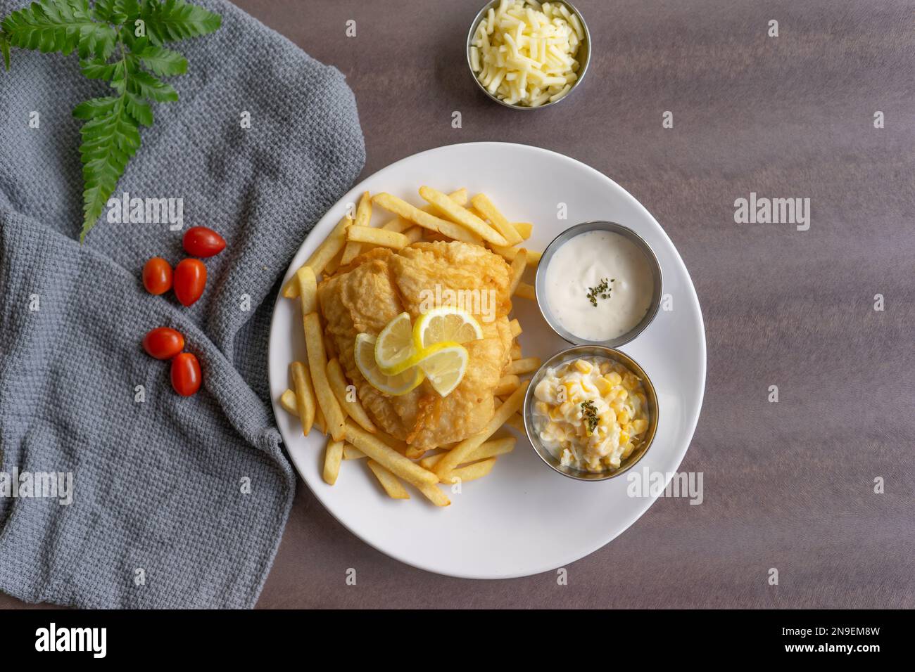 Ein Stück Fisch mit Chips auf einem weißen Teller auf einem Holztisch Stockfoto