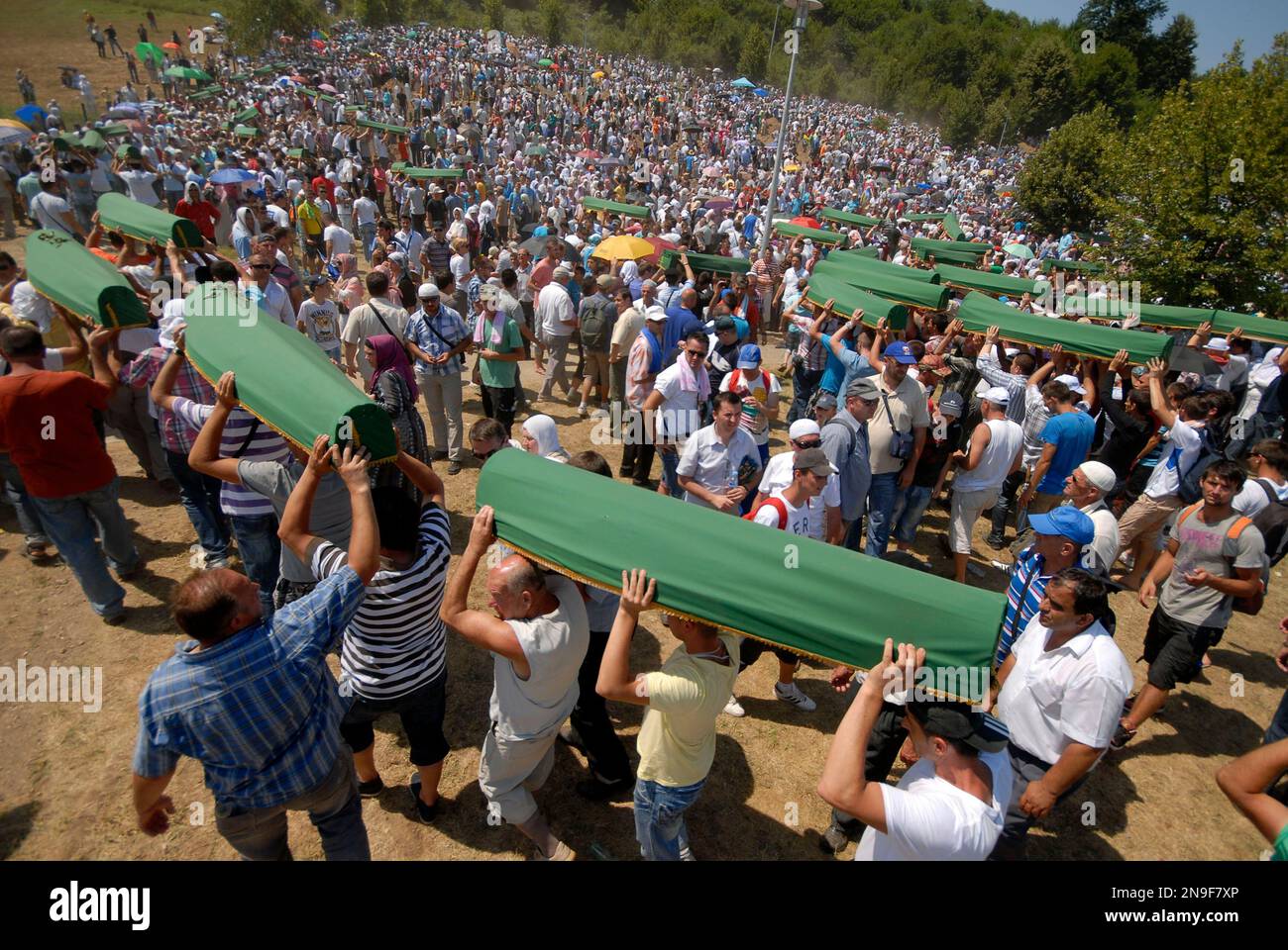 Bosnian Muslim men carry coffins of their relatives during a mass