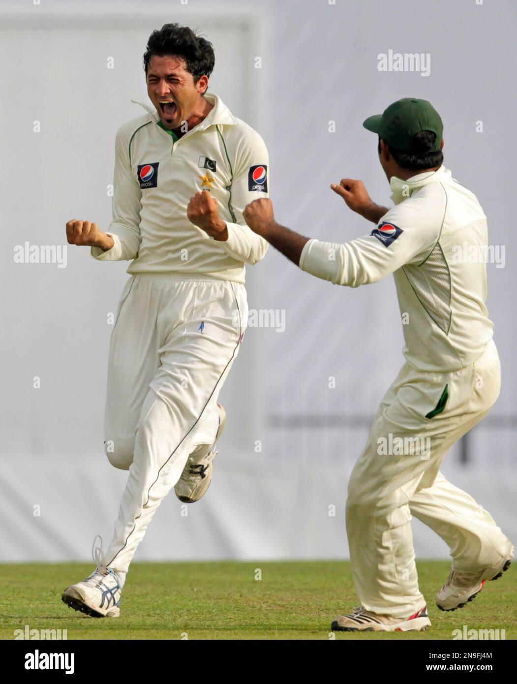 Pakistan's bowler Junaid Khan, left, with teammate Asad Shafiq celebrates after taking the wicket of Sri Lankan batsman Kumar Sangakkara, unseen, on the first day of their third and final test cricket match in Pallekele, Sri Lanka, Sunday, July 8, 2012. Sri Lanka leads the series 1-0. (AP Photo/Eranga Jayawardena) Stockfoto