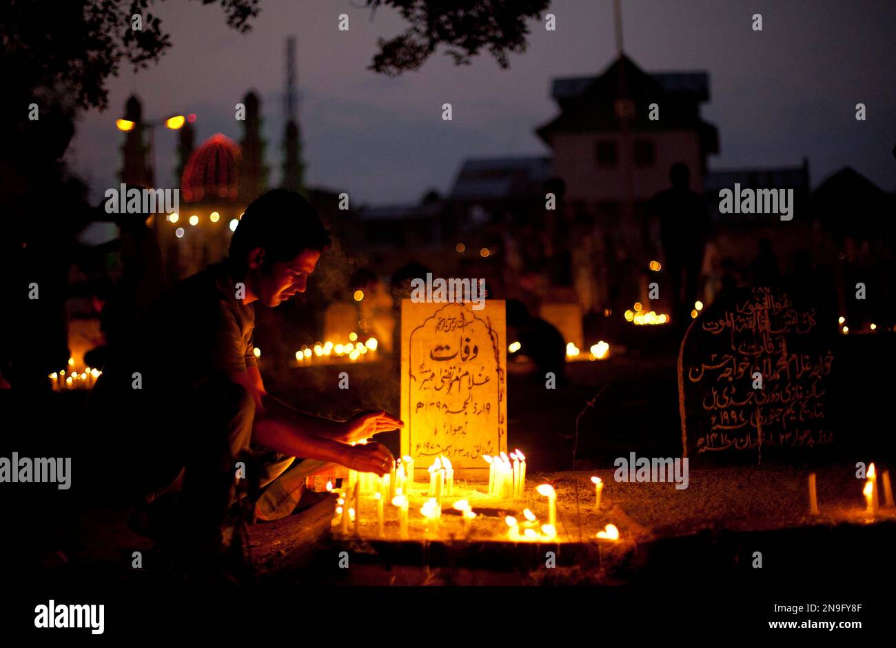 A Kashmiri shiite Muslim boy lights a candle at the grave of his ...