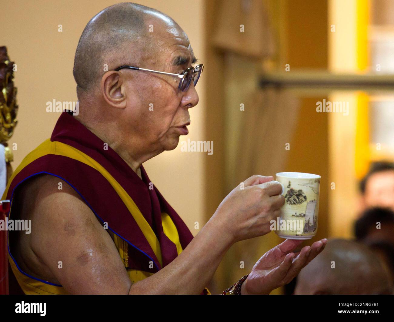 Tibetan spiritual leader the Dalai Lama holds his cup of tea during a ...