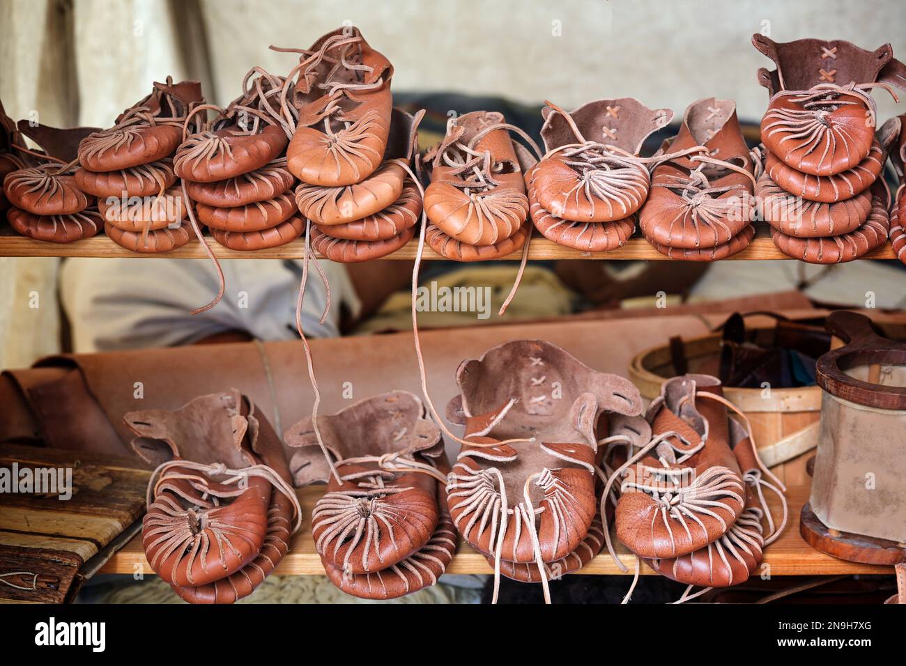 Handgefertigte historische Lederschuhe zum Verkauf auf Regalen auf einem mittelalterlichen Markt, Kopierraum, ausgewählter Fokus, schmale Schärfentiefe Stockfoto