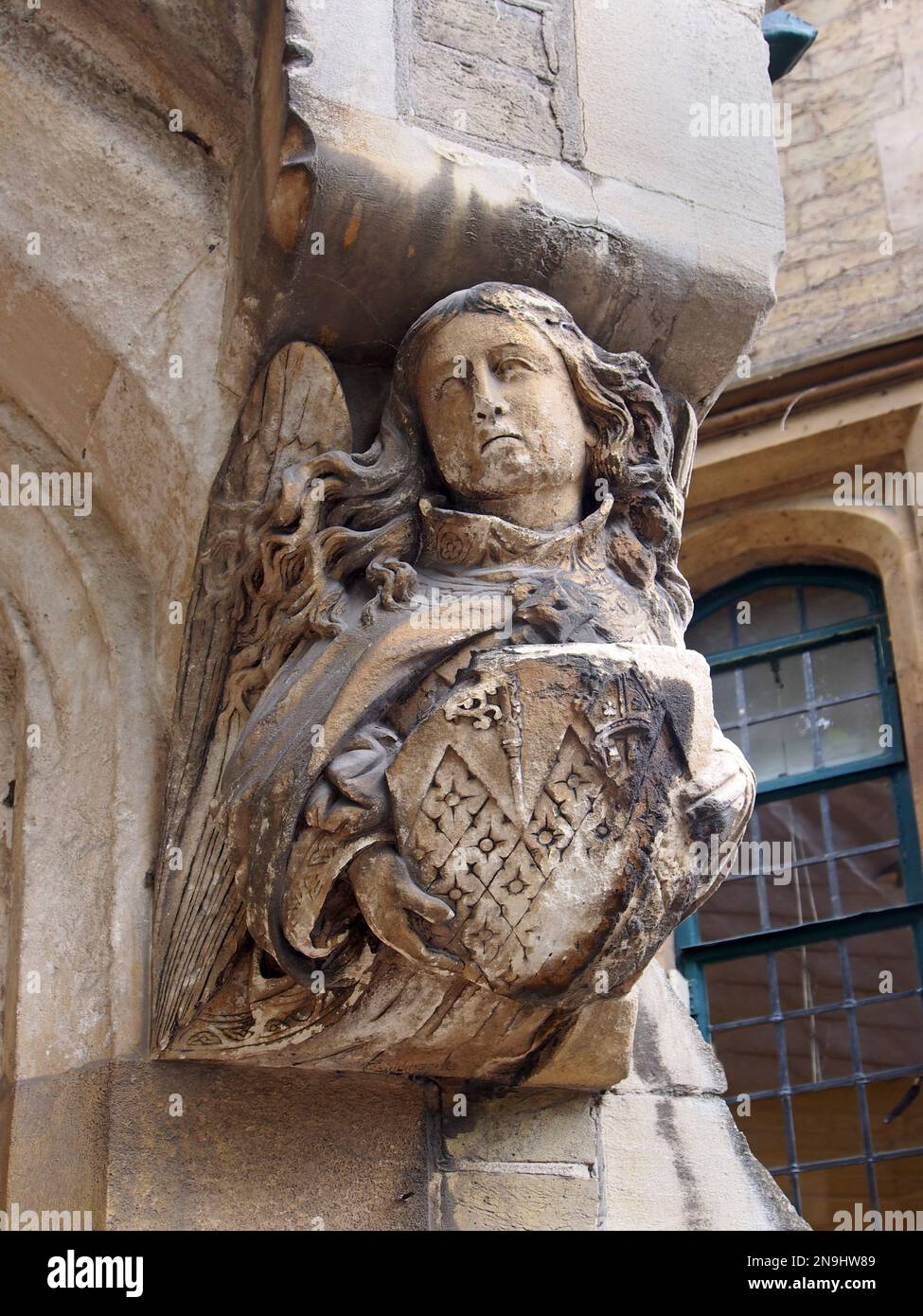 Steinschnitzerei eines Engels, der ein Wappen in der Hand hält, das Wetter geschlagen und erodiert, vor einer alten Kirche in der Nähe der Westminster Abbey Stockfoto