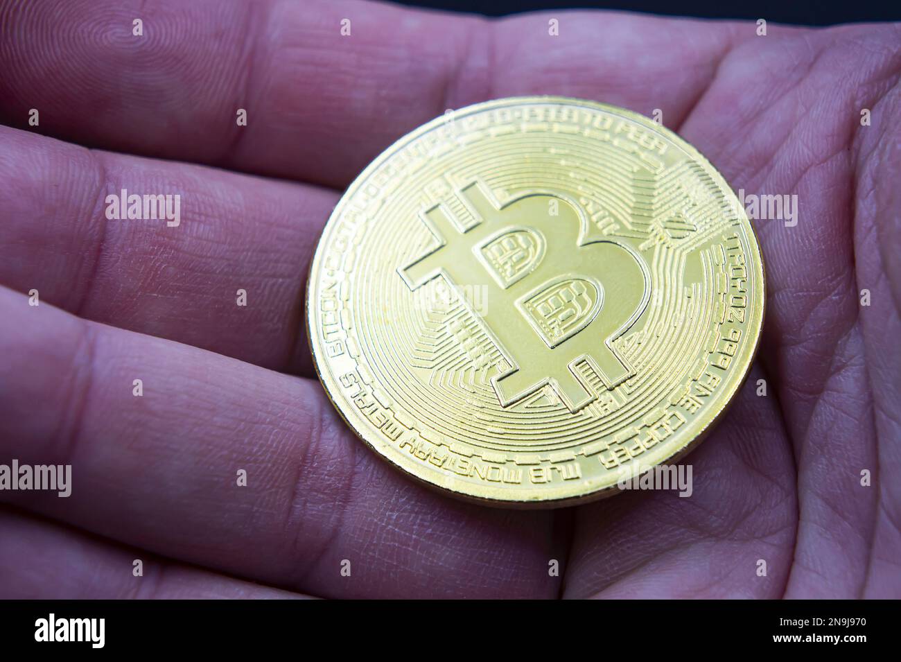 Finger halten Bitcoin golden auf schwarz isoliert. Handgriff Gold Bitcoin Crypto Ditital Money Konzept. Auf schwarzem Hintergrund betrachten wir eine virtuelle Währung Stockfoto