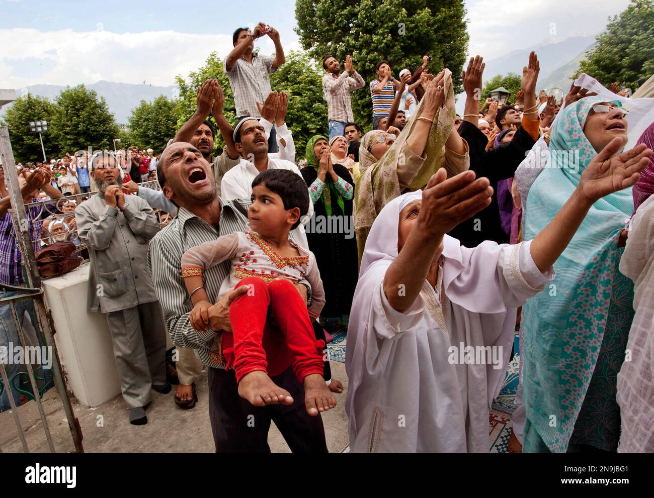 A Kashmiri Muslim man holds his daughter reacts after the head priest ...