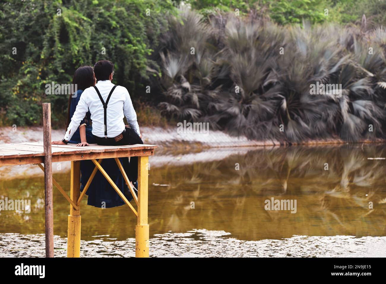 Ein junges Paar sitzt am See und genießt den Valentinstag. Stockfoto