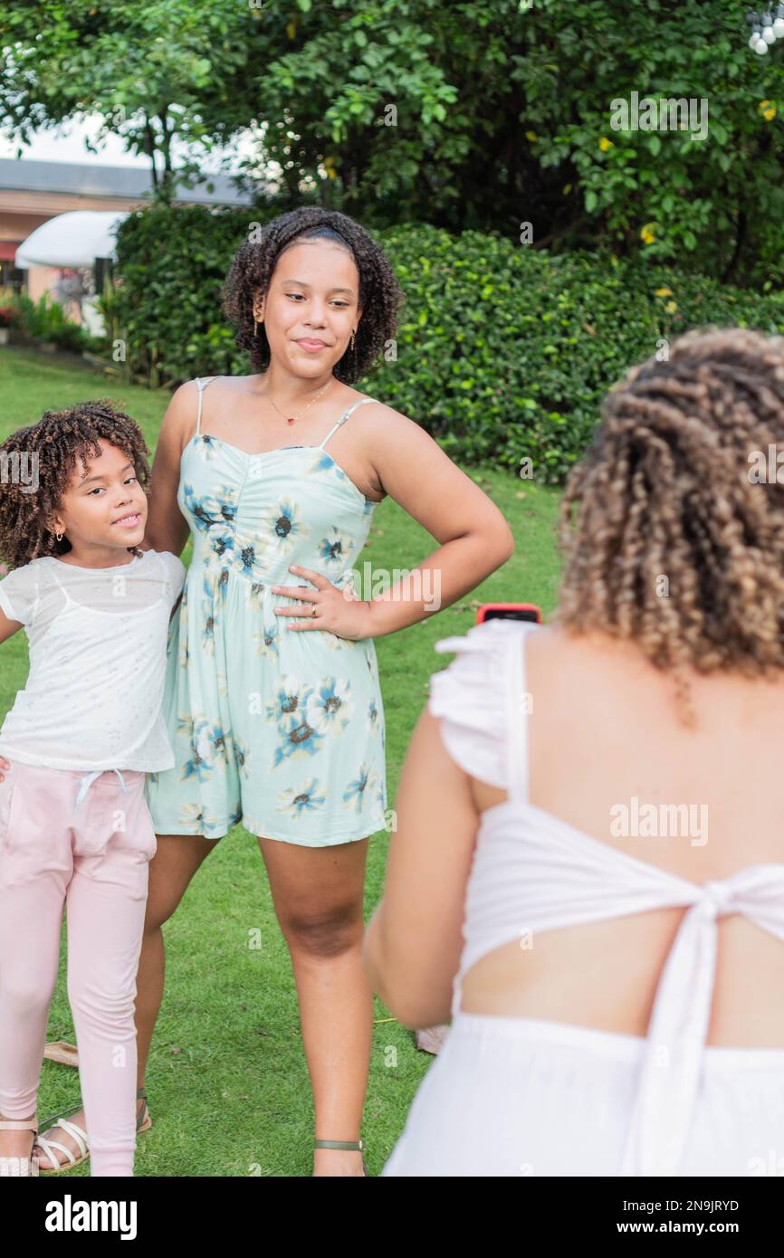 Lateinische Mutter macht ein Handyfoto ihrer Töchter im Freien Stockfoto
