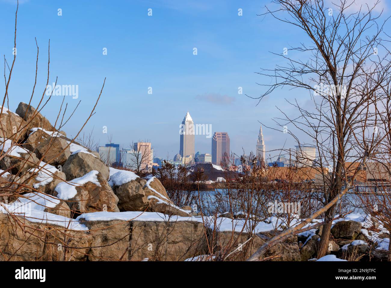 Der Edgewater Park in Cleveland, Ohio, bietet einen schönen Blick auf die Skyline von Clevelands, die sich hinter Felsen und Sträuchern am winterlichen Ufer des Lake Erie erstreckt. Stockfoto