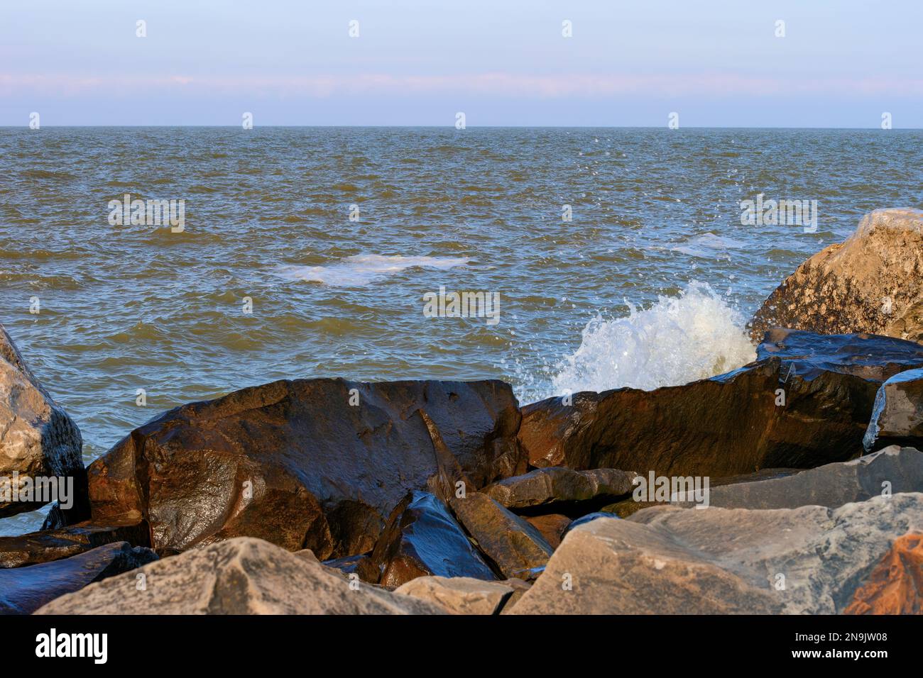 Am winterlichen Ufer des Lake Erie im Edgewater Park in Cleveland, Ohio, treffen die Wellen des Windes auf die Felsen. Stockfoto