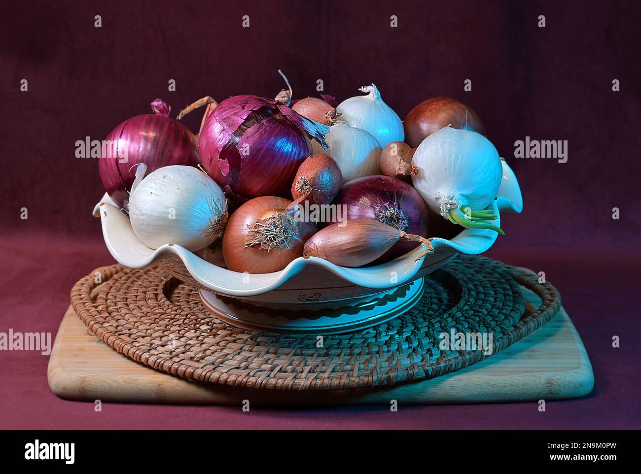 Zusammensetzung von roten, weißen und goldenen Zwiebeln, Schalotten. Fotografiert in künstlichem Licht. Stockfoto