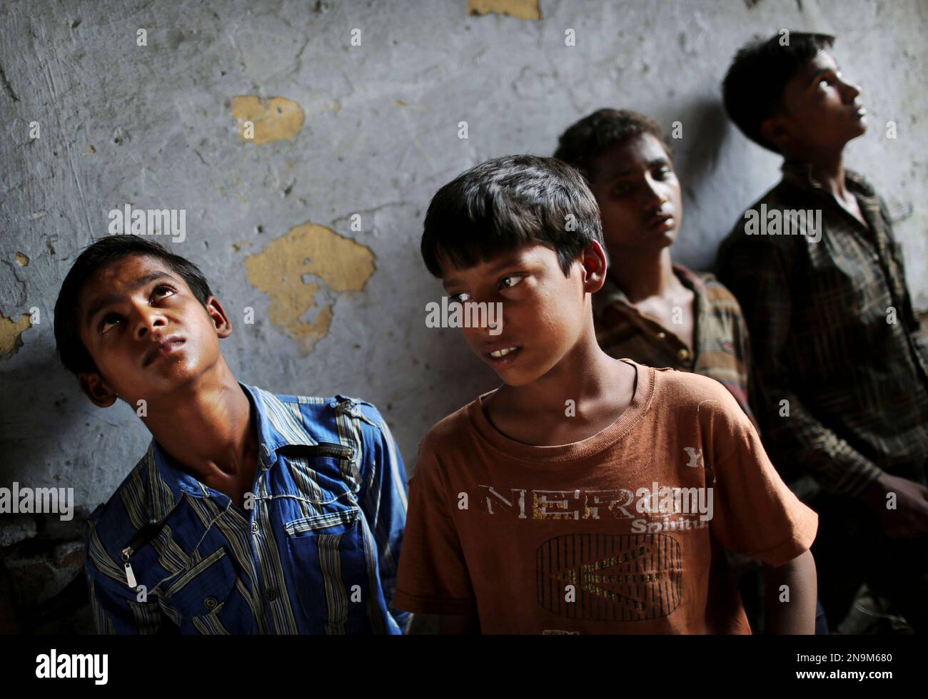 Young Indian bonded child laborers wait to be taken away after being rescued during a raid by workers from Bachpan Bachao Andolan, or Save the Childhood Movement, at a garment factory in New Delhi, India, Tuesday, June 12, 2012. Raids on factories in the Indian capital revealed dozens of migrant kids hard at work Tuesday despite laws against child labor. Police rounded up 26 children from three textiles factories and a metal processing plant, but dozens more are believed to have escaped. Those captured had all come to New Delhi from the states of Bihar and Uttar Pradesh. (AP Photo/Kevin Frayer Stockfoto