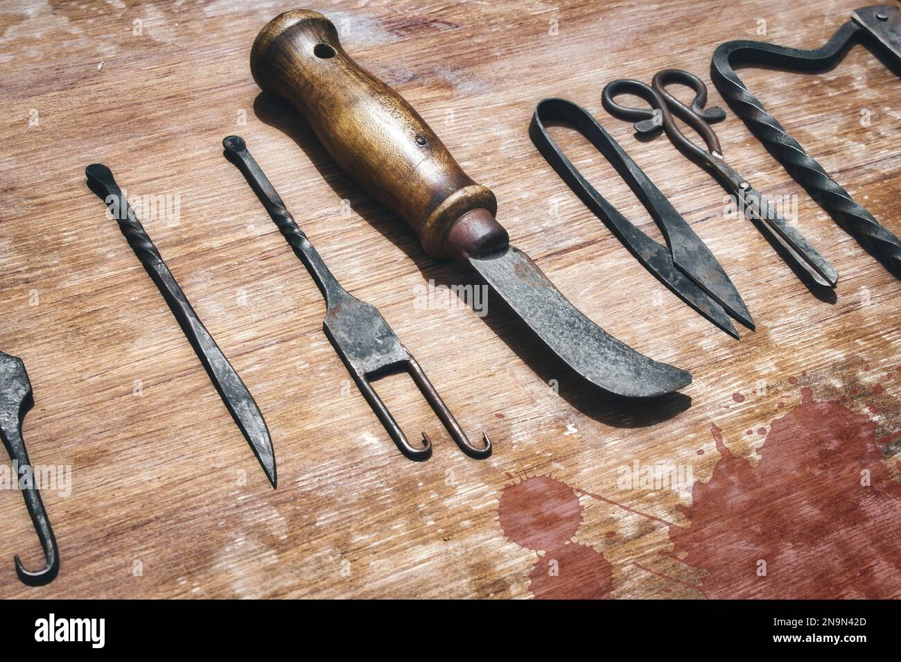 Eine Auswahl an mittelalterlichen chirurgischen Instrumenten auf einem blutverschmutzten Holztisch Stockfoto
