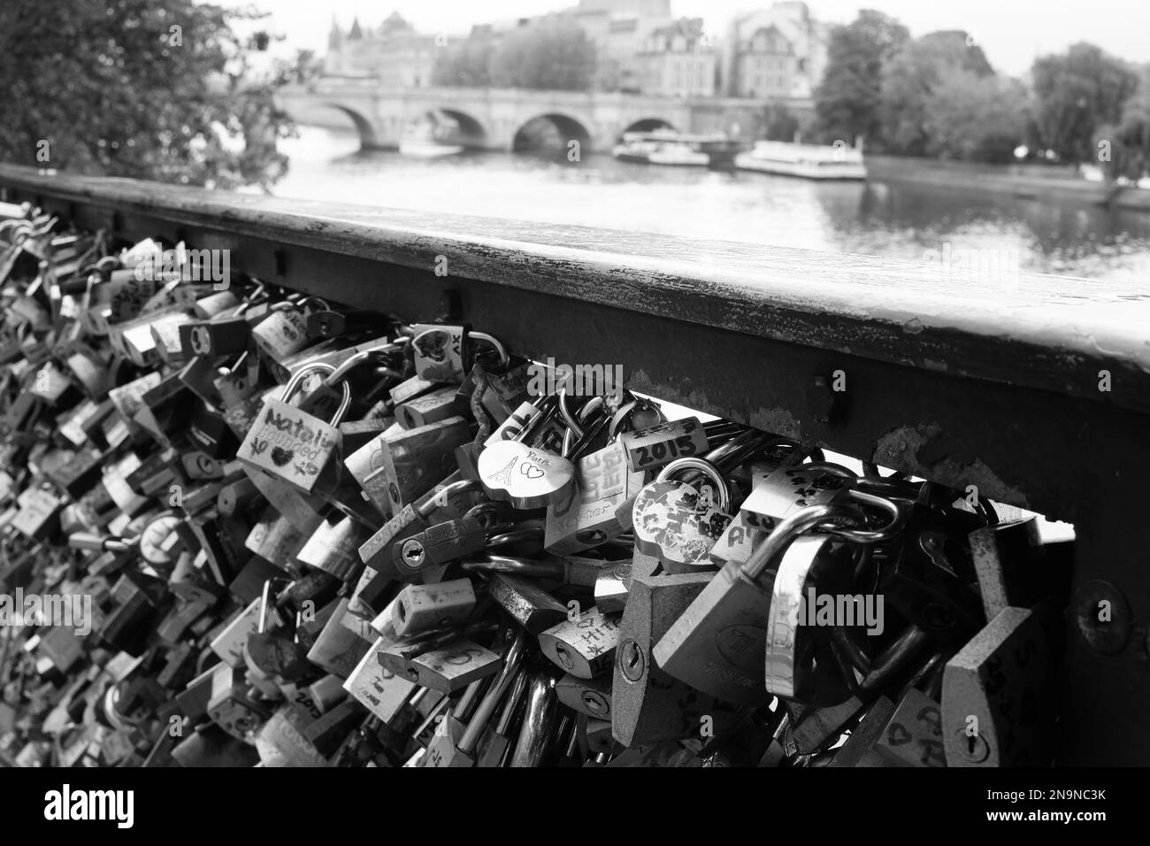 Eine Graustufenaufnahme der Vorhängeschlösser der Liebe auf einem Brückenzaun auf der seine in Paris Stockfoto