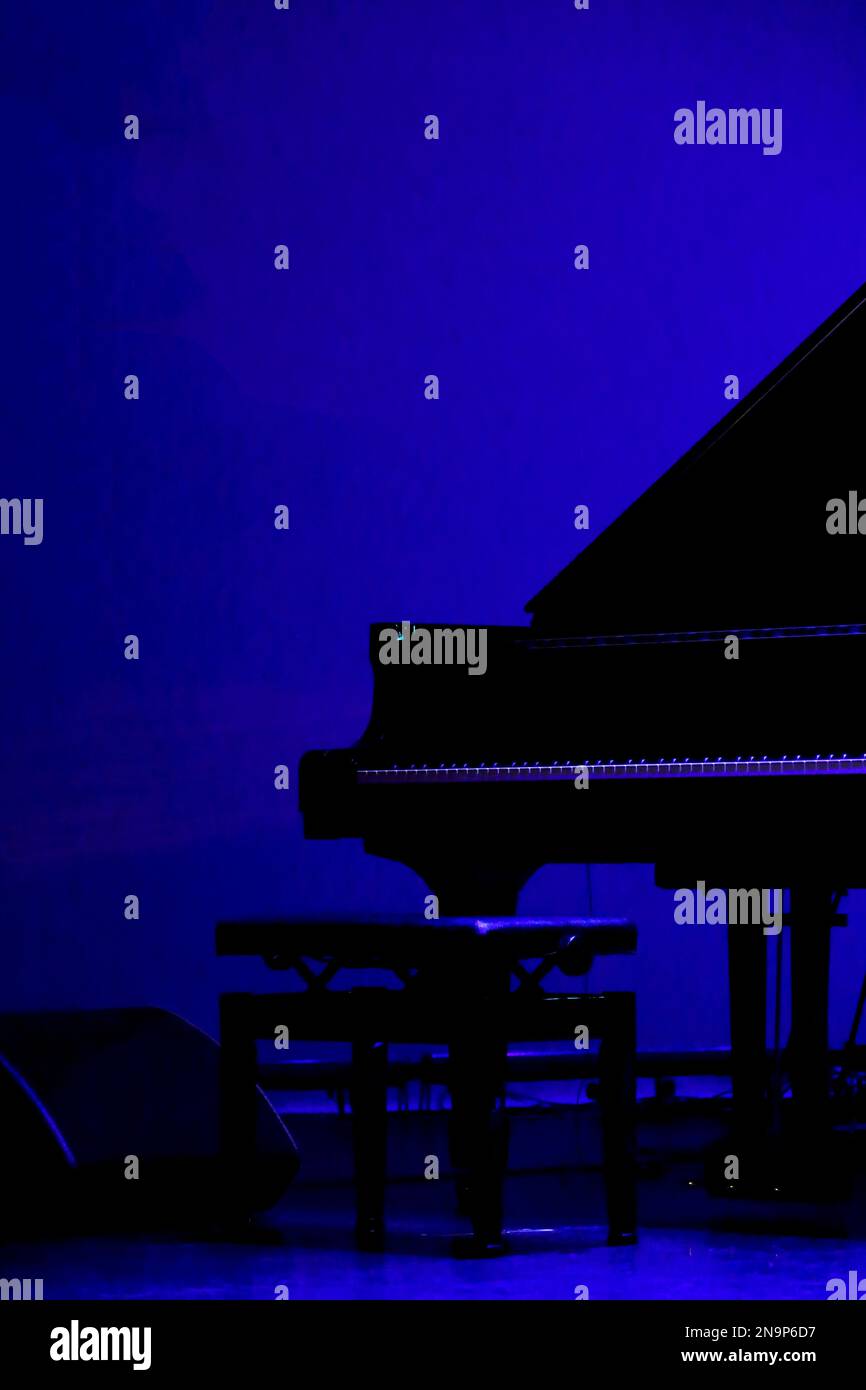 Ein großes Klavier, das vor der Vorstellung auf die Bühne eines schwach beleuchteten Live-Hauses gestellt wird Stockfoto