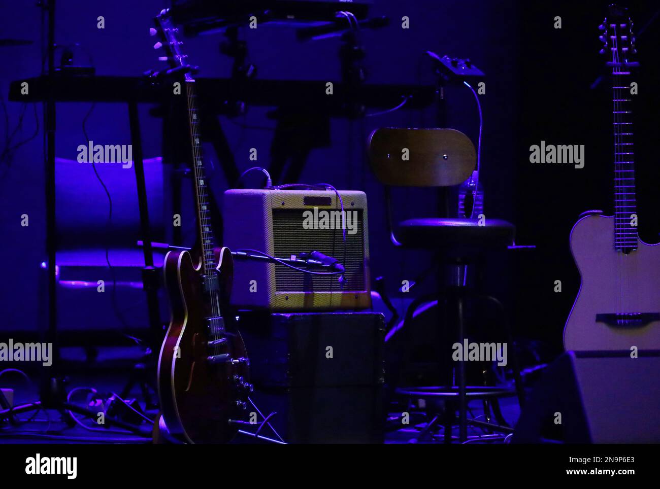 Eine Gitarre, die vor der Vorstellung auf die Bühne eines schwach beleuchteten Live-Hauses gestellt wird Stockfoto