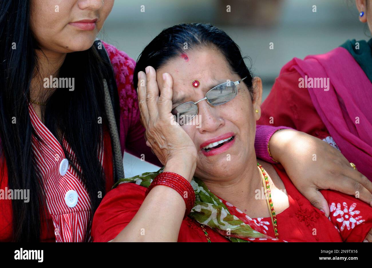 Unidentified people comfort each other as bodies of relatives, victims of a plane crash, are brought in to the nearby city of Pokhara, Nepal, Monday, May 14, 2012. A plane crashed into a mountain in the Himalayas while trying to land at Jomsom Airport, 200 kilometers (125 miles) northwest of the capital, Katmandu, Monday, killing 15 people and critically injuring six. (AP Photo/Krishnamani Baral) Stockfoto