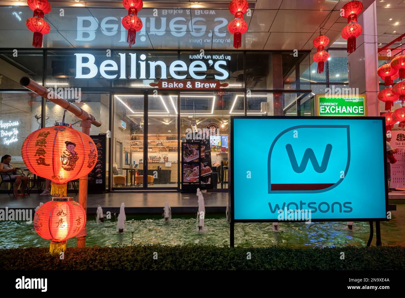 Beleuchtetes Bellinee's Cafe und Werbung für andere Dienstleistungen in der Limelight Avenue Mall, beleuchtet für den Abend; Phuket Town, Phuket, Thailand Stockfoto