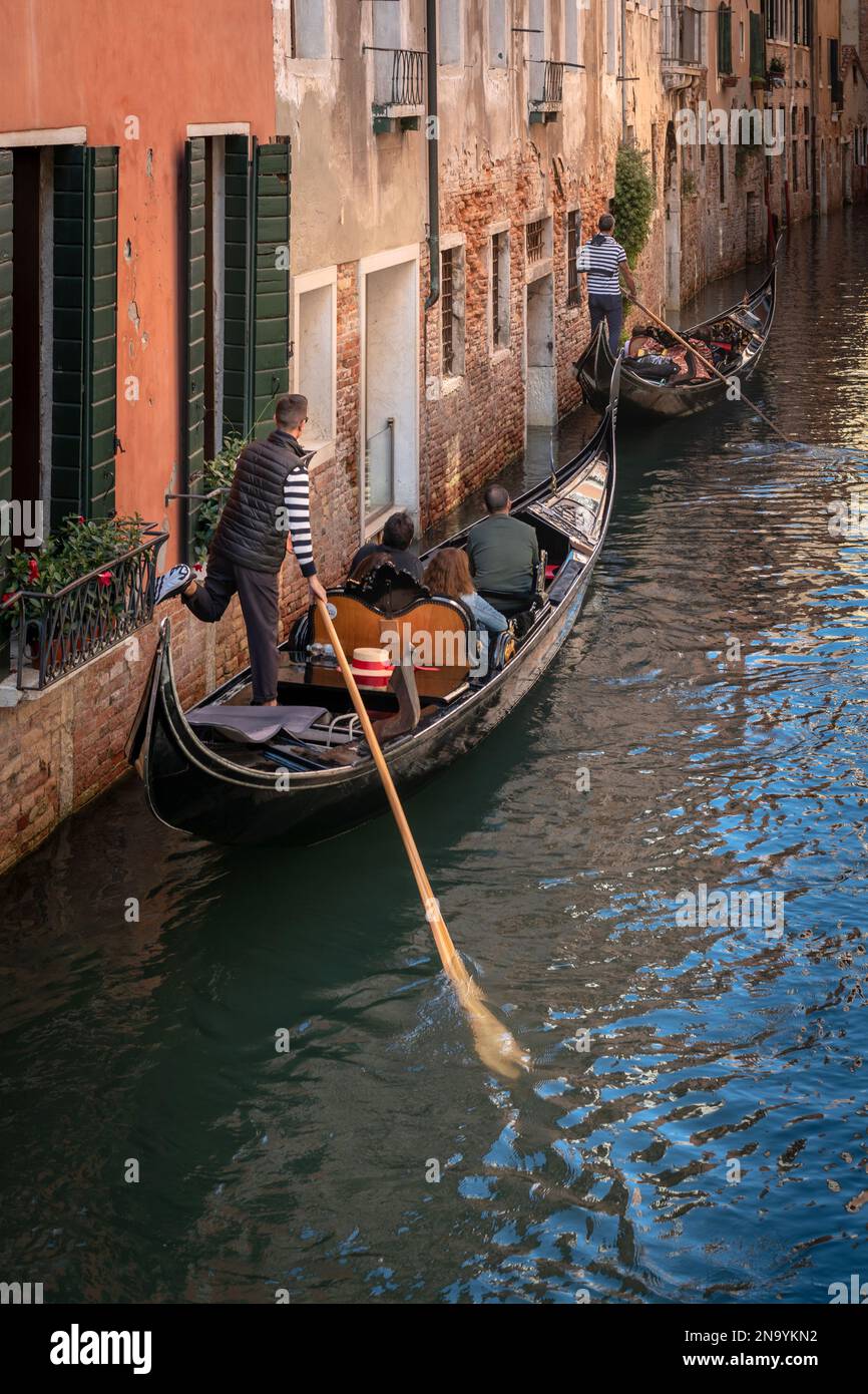 Gondoliere schiebt die Gondel von der Wand auf einem Kanal in Venedig Stockfoto