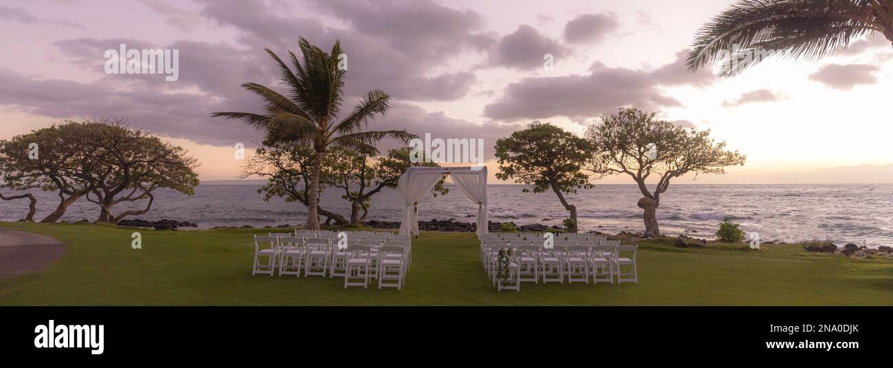 Vorbereitung für eine Hochzeit im Freien bei Sonnenuntergang entlang der Küste einer hawaiianischen Insel mit Blick auf das Meer und den Horizont Stockfoto