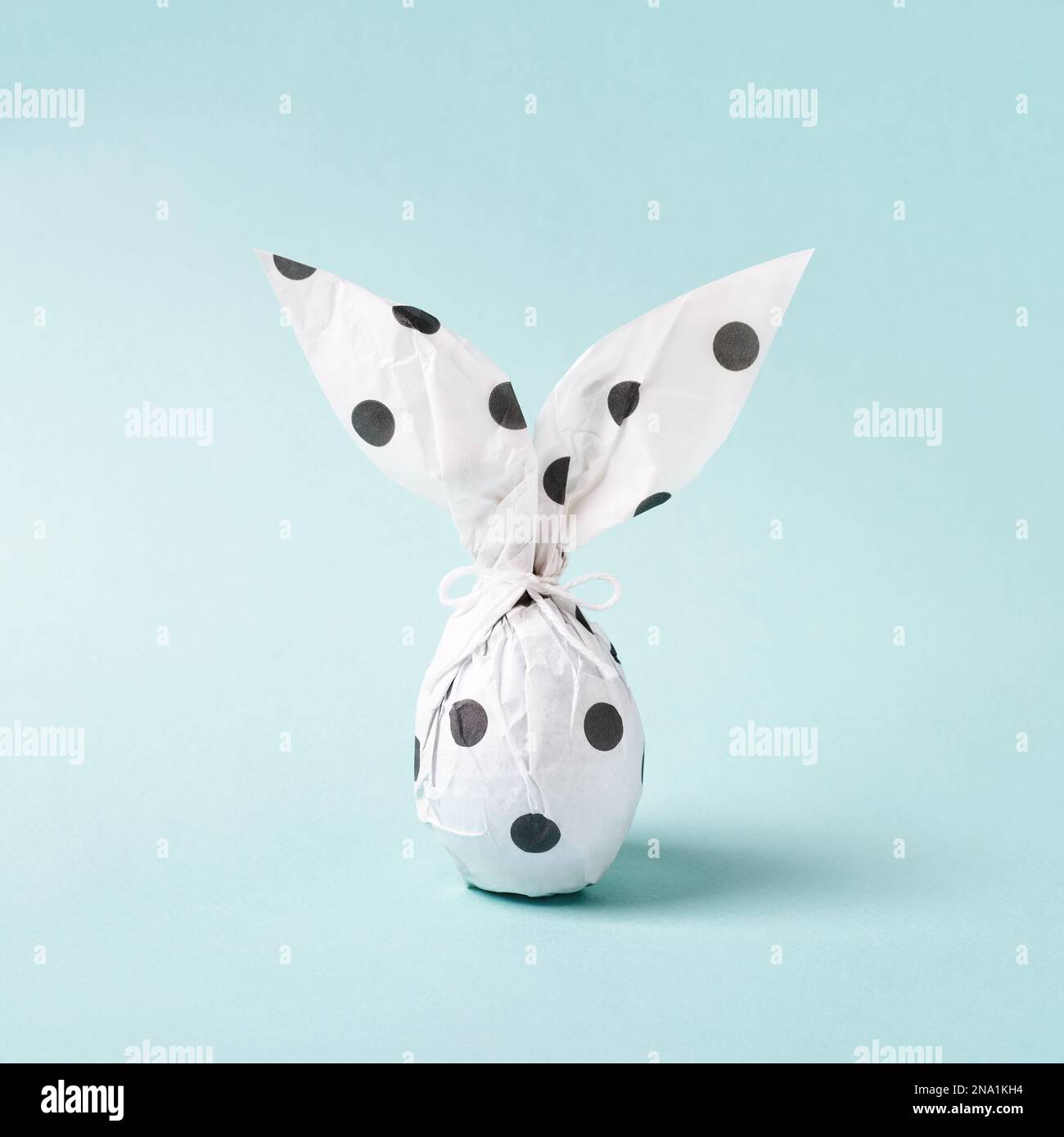 Osterhase in Geschenkpapier. Selbstgemachte Geschenkideen. Osterei als weißes Kaninchen. Ostergrußkarte, minimalistisch. Stockfoto