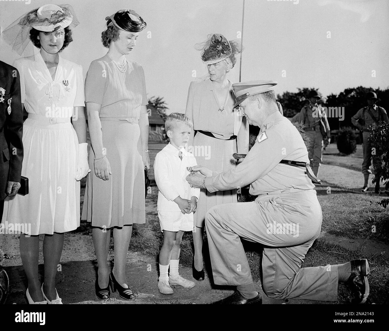 Major General Sherman Miles of the First Service Command, pins the Oak Leaf Cluster on John K. Waters, Jr., son of Lt. Col. and Beatrice Patton Waters, in Melrose, Mass., July 19, 1943. Mrs. Waters, left, who received the award in behalf of her husband, now a prisoner of the Germans, is the daughter of Lt. Gen. George S. Patton, Jr. Mrs. Patton, wife of the lieutenant general, stands in the background. (AP Photo/Dan Grossi) Stockfoto