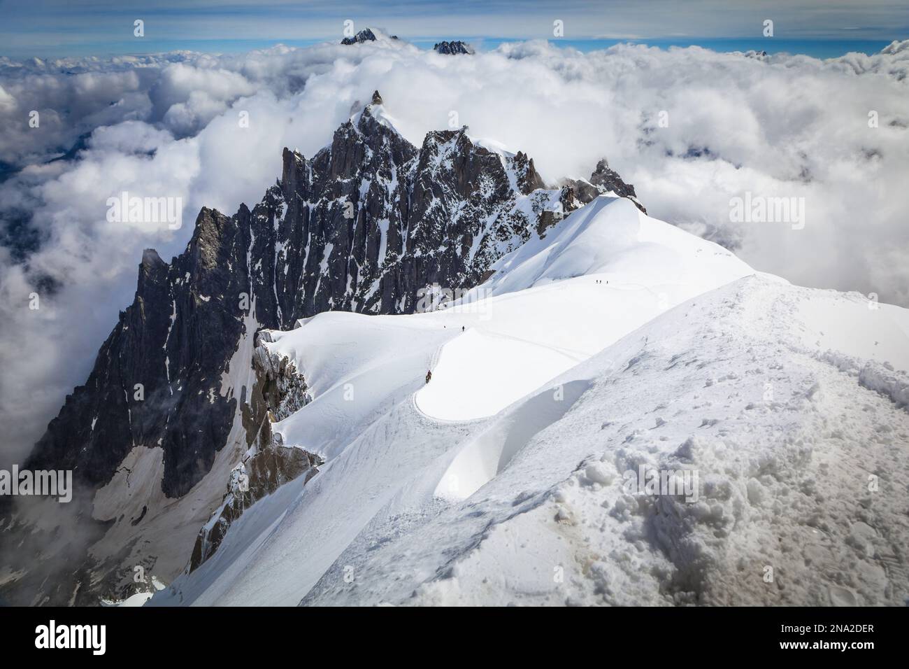 Kletterer verlassen Aiguille du Midi. Der Gipfel von Aiguille du Plan ist im Hintergrund. Chamonix - Mont Blanc, Alpen, Frankreich, Europa, Sommer. Stockfoto